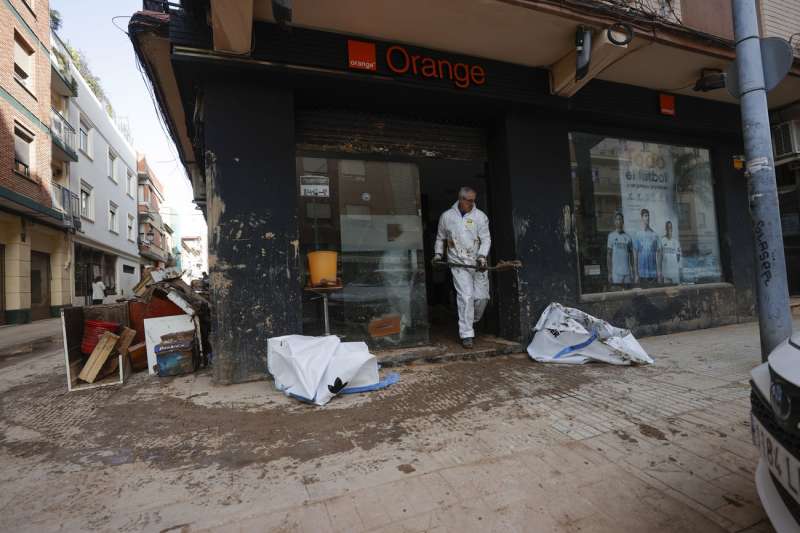 Un hombre saca lodo con una pala de la tienda de Orange en Paiporta este viernes, un mes despus de la DANA que asol el municipio. EFE Raquel Segura
