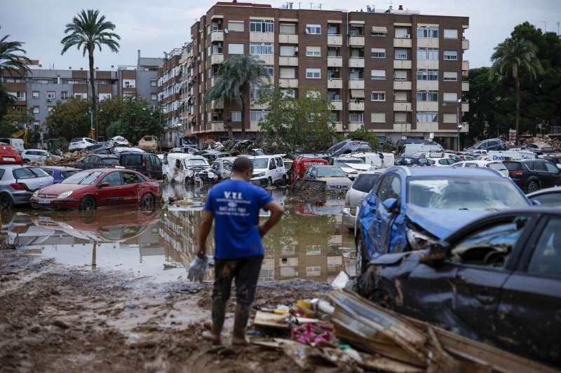 Un hombre junto a varios coches arrastrados por el agua tras el paso de la dana, en Paiporta este viernes. EFE Biel Alio