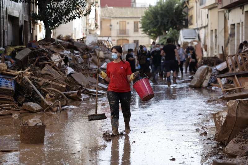 Varias personas retiran el lodo acumulado en una calle de la localidad valenciana de Paiporta, este sbado. EFE