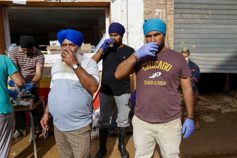 Voluntarios de India colaboran en limpiar las calles de Paiporta tras la dana.- EFE Jorge Zapata
