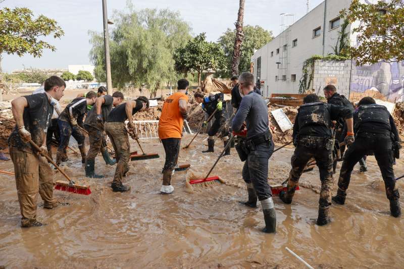 Voluntarios y fuerzas de seguridad trabajan para despejar una calle de Paiporta, este martes. EFE Manuel Bruque
