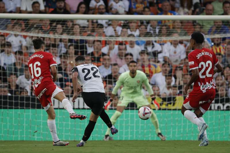 El delantero del Valencia, Luis Rioja, golpea el balón ante el guardameta argentino del Girona, Paulo Gazzaniga, para conseguir el primer gol del equipo valencianista durante el encuentro correspondiente a la sexta jornada de Laliga EA Sports jugado en el estadio de Mestalla, en Valencia. EFE/Manuel Bruque.
